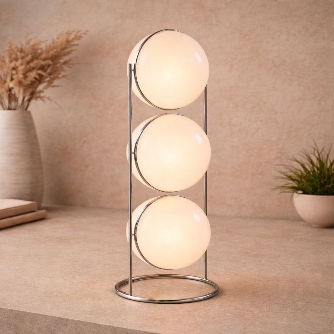 Modern table lamp with three spherical glass shades on a wooden surface.