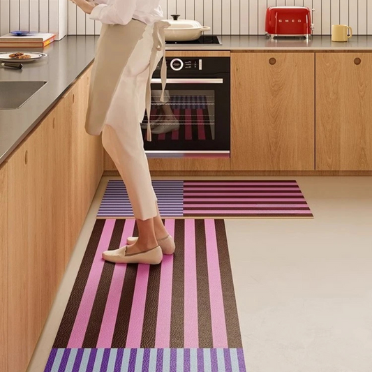 Person walking on a striped rug in a kitchen with wooden cabinets and a colorful rug.
