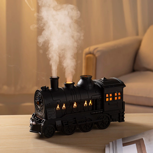 Black train-shaped humidifier emitting steam on a wooden surface with a blurred background