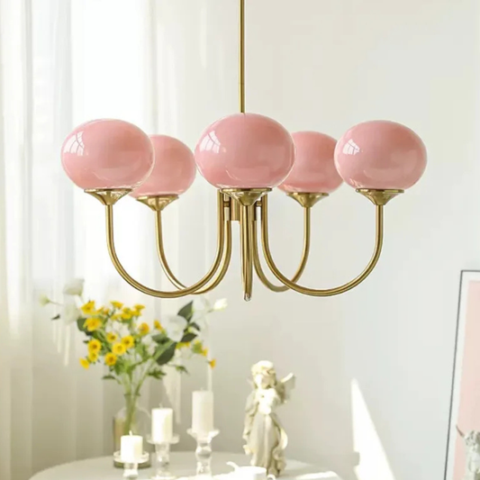 Chandelier with pink glass globes and gold fixtures in a room setting.
