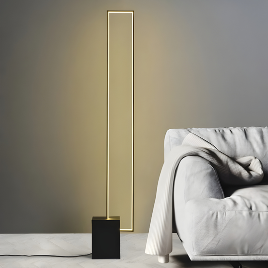 Modern floor lamp with a sleek design next to a gray sofa against a neutral wall.