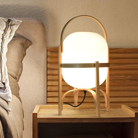 Wooden table lamp on a nightstand next to a bed