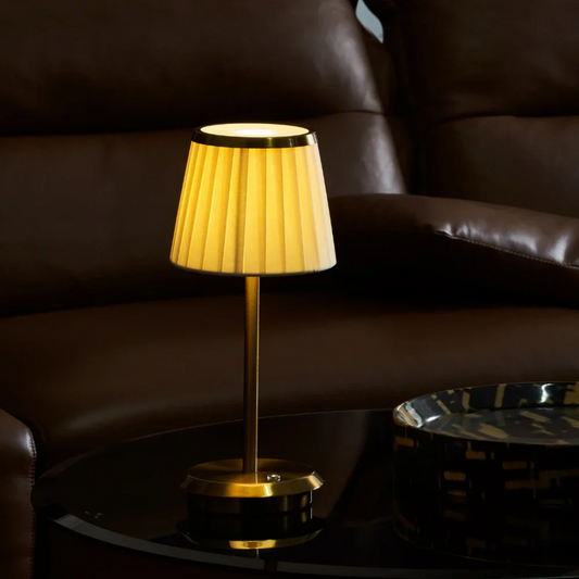 Yellow table lamp on a dark surface with a brown leather chair in the background