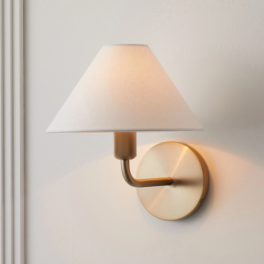 Wall-mounted lamp with a white shade and gold fixture on a light gray wall.