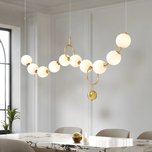 Modern chandelier with gold accents and white glass bulbs in a room with a marble table and chairs.
