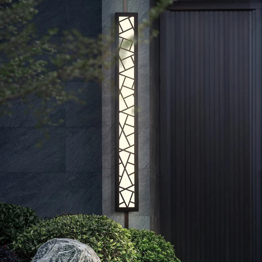Decorative outdoor light fixture on a garden path next to a building.